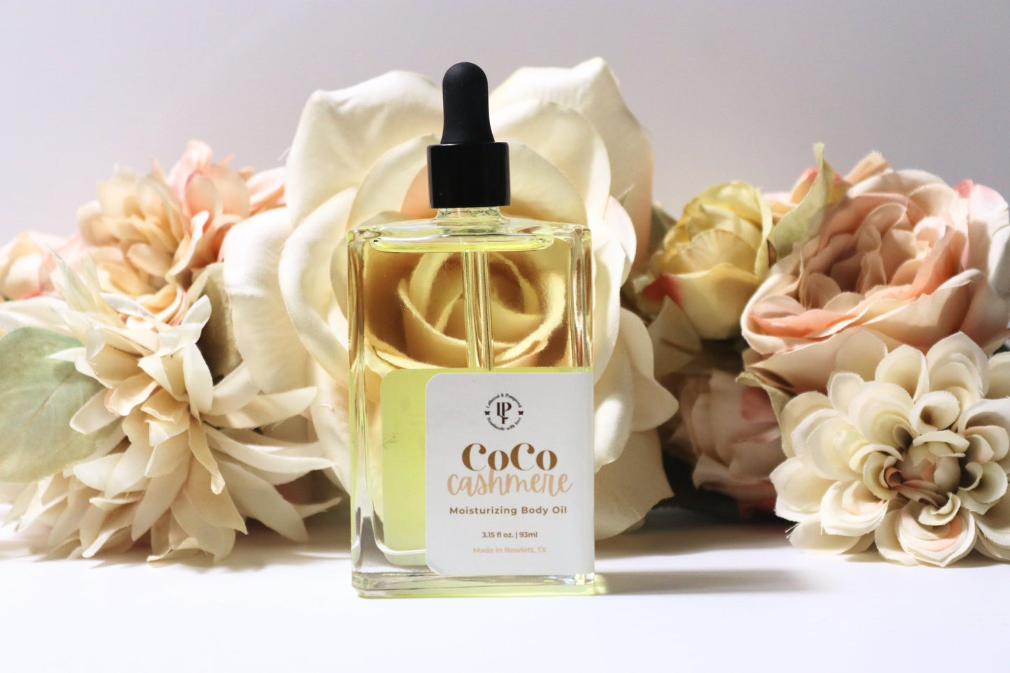 Coco Cashmere body oil in a clear glass bottle with scent notes of coconut, cocoa butter and cedarwood