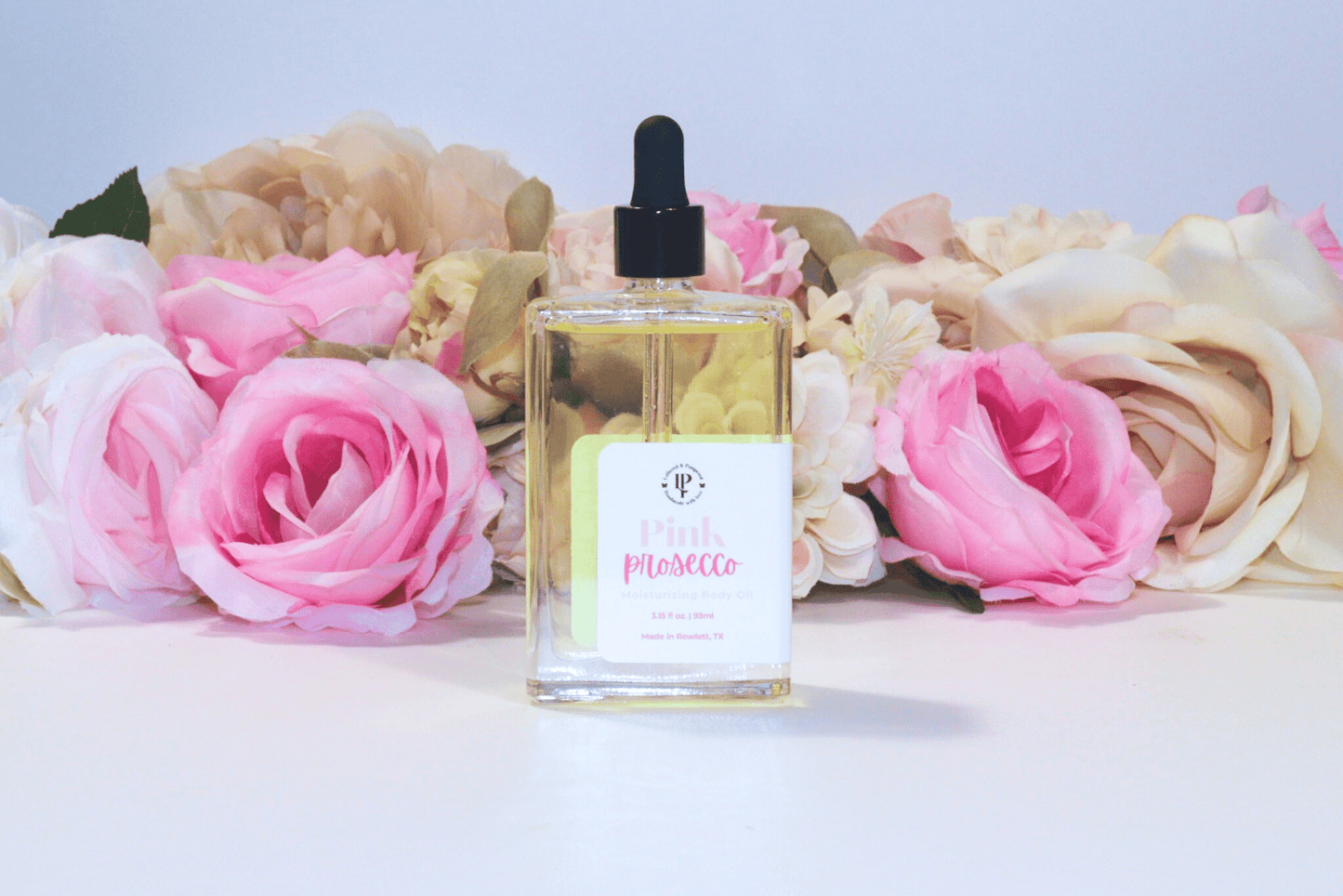 Pink Prosecco body oil in a clear glass bottle with scent notes of Citrus, Cranberry, Champagne and Musk